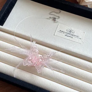 Detail der rosa Kristall-Schmetterlingskette mit zarten Federn an einem klaren Band