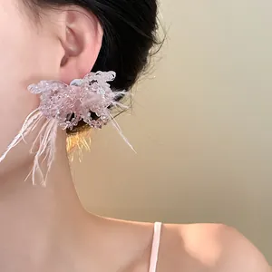 Detailansicht eines eleganten Ohrrings mit rosa Federn und Kristallschmetterling