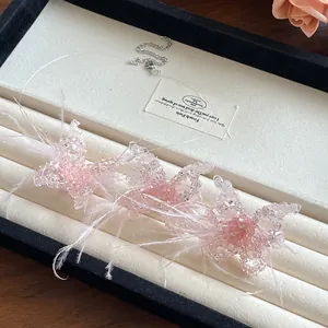 Detailansicht einer rosa Kristall-Schmetterlingskette mit zarten Federakzenten.