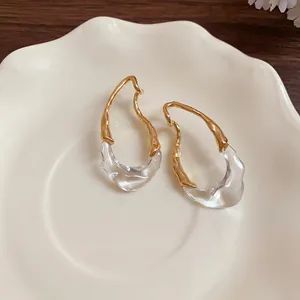Orecchini a goccia in resina placcati oro 18K su un piatto di ceramica bianca minimalista