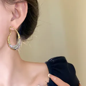 Dettaglio di orecchini geometrici irregolari placcati oro 18K indossati dalla modella