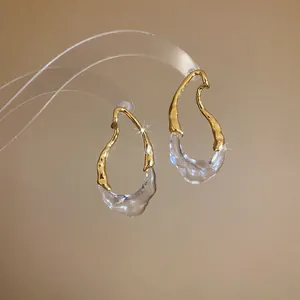 Dettaglio ravvicinato della trama ondulata degli orecchini a goccia in oro e resina