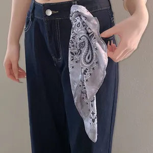 Detail shot of a stylish grey paisley pattern bandana tied to denim jeans as an accessory