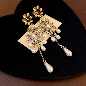 Vintage gold flower chandelier earrings with elegant teardrop pearls on black velvet.