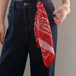 Detailed view of a red paisley print bandana tied on denim jeans for styling