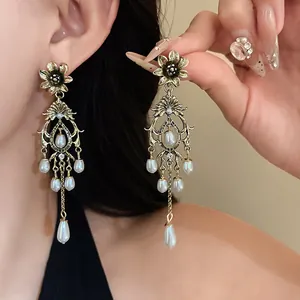 Close-up of vintage gold-tone flower earrings with elegant hanging teardrop pearls.