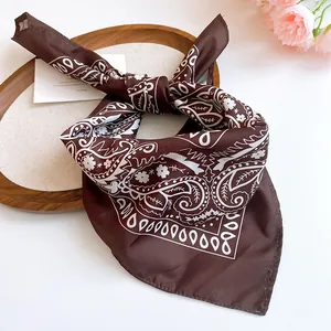 Close-up detail of a brown sunflower print silk scarf arranged on a wooden display tray.