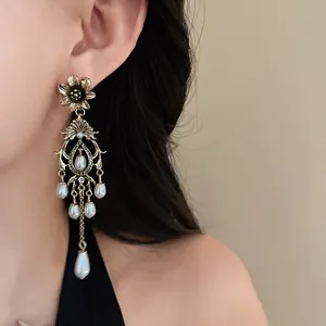 Close-up of vintage gold floral earrings featuring elegant white faux pearl tassels
