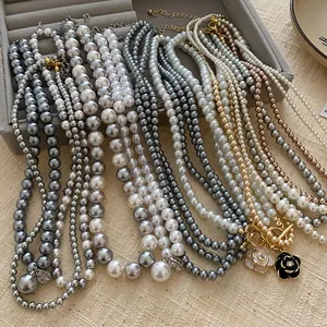 Close-up detail view of elegant grey and white pearl necklaces with floral charms.
