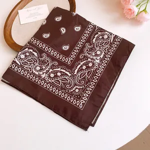 Detailed close-up of a brown paisley print bandana scarf with floral accents on a white table