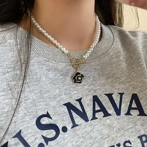 Close-up of French vintage pearl necklace with black flower pendant and T-bar clasp.