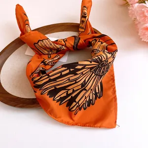Close-up of orange silk scarf with black stylized sunflower print tied in a knot