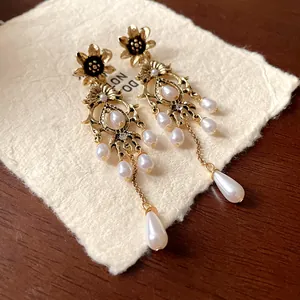 Detailed view of vintage gold floral earrings featuring drop pearls and sparkling crystals