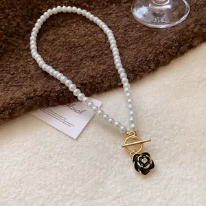 Close-up of a vintage pearl necklace featuring a black rose pendant and gold clasp.