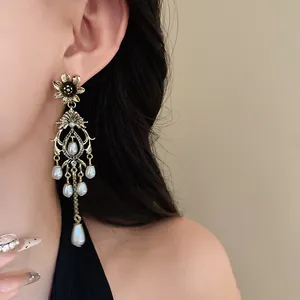 Close-up of vintage gold-toned flower drop earrings with elegant faux pearl accents.