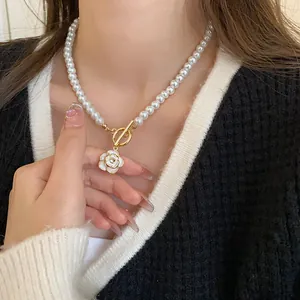 Close-up of a white pearl necklace with a vintage gold camellia flower pendant