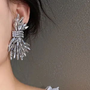 Detailed close-up showing silver-finish wing earrings with sparkling crystals on ear