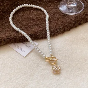 Detail view of white pearl necklace with camellia flower pendant and gold OT clasp