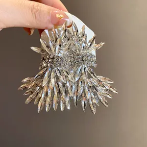 Macro detail of sparkly oversized crystal wing earrings held on a white jewelry display card