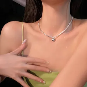 Detailed macro shot of an elegant silver heart pendant and pearl necklace on model