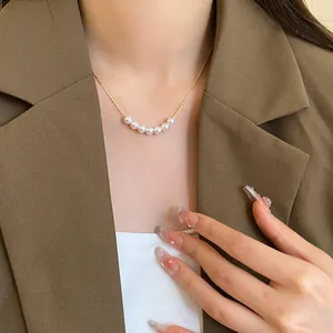 Close-up detail of an elegant French vintage pearl necklace worn with a brown blazer
