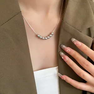 Close-up of elegant gray metallic bead necklace on a thin silver chain worn with a blazer