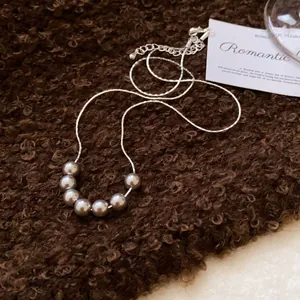 Detailed view of vintage grey pearls and fine silver chain on a warm brown texture