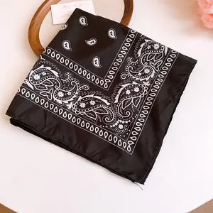 Detailed view of a stylish black and white paisley print bandana made of smooth, silky fabric.
