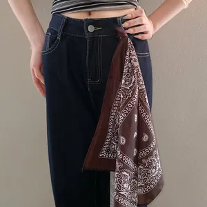 Fashionable brown paisley print bandana styled as a chic waist accessory on dark jeans