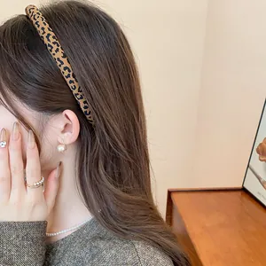 Elegante cerchietto leopardato retrò e accessori con perle indossati da una donna