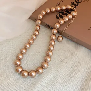 Close-up of elegant champagne faux pearl necklace featuring a gold-toned extender chain