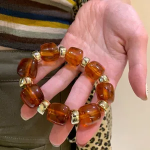 Detailed view of vintage amber-style acrylic bracelet with gold spacers held in hand