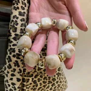 Close-up of acrylic marbled cube beads and gold-toned accents on a chunky bracelet.