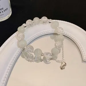 Bracciale di perle occhio di gatto con ciondoli a luna e campanello da donna.