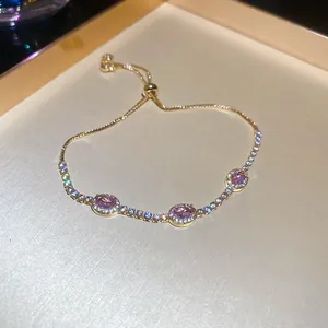 Elegante pulsera dorada ajustable con tres dijes ovalados de resina rosa y pavé de piedras