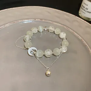 Dettaglio del bracciale di perle occhio di gatto con ciondoli luna e campanello silver