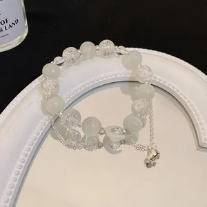 Primo piano di bracciale in occhio di gatto con campanello d'argento e luna su specchio.