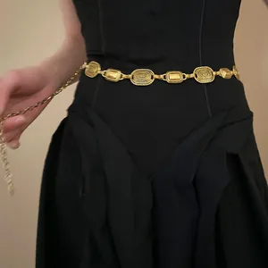 Bohemian vintage style gold textured metal waist chain belt on black dress detail view.