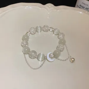 Dettaglio del bracciale con perline occhio di gatto bianco, ciondolo luna e campanello