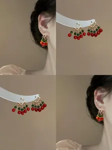 Macro view of vintage Chinese palace style beaded earrings with red and green clusters.