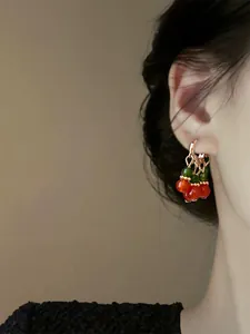 Detail view of retro palace style beaded cherry earrings worn on ear