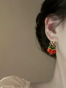 Vintage red and green beaded cherry earrings worn on ear showing elegant jewelry detail for women