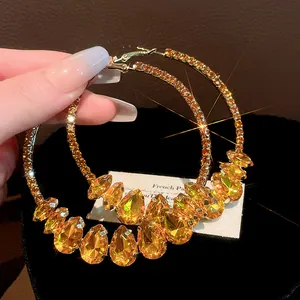 Close-up detail of vintage style oversized hoop earrings featuring amber water-drop crystals