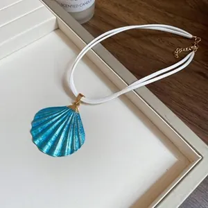 Nahaufnahme einer blauen Muschelhalskette mit weißer Doppelschnur und Goldverschluss