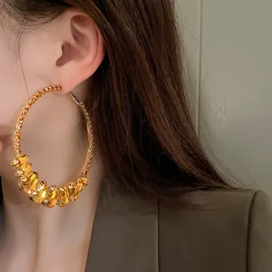 Close-up of exaggerated vintage gold hoop earrings with amber water drop crystal accents