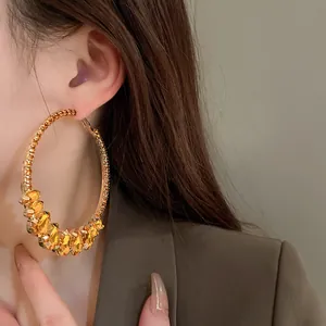 Detailed close-up of retro gold hoop earrings with amber water-drop crystals on model.