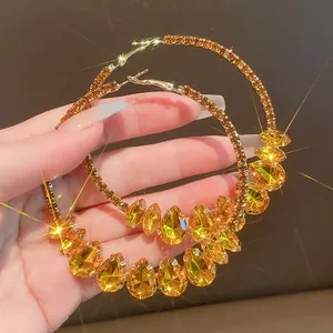 Close-up of sparkling amber teardrop crystal hoop earrings with silver needle