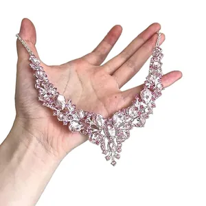 Luxuriöse silberne Halskette mit rosa und weißen Tropfenkristallen in der Hand