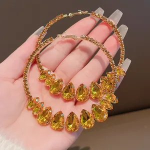 Close-up detail of exaggerated retro hoop earrings with yellow water-drop crystals.