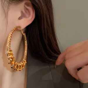 Close-up of oversized gold hoop earrings featuring amber teardrop crystals